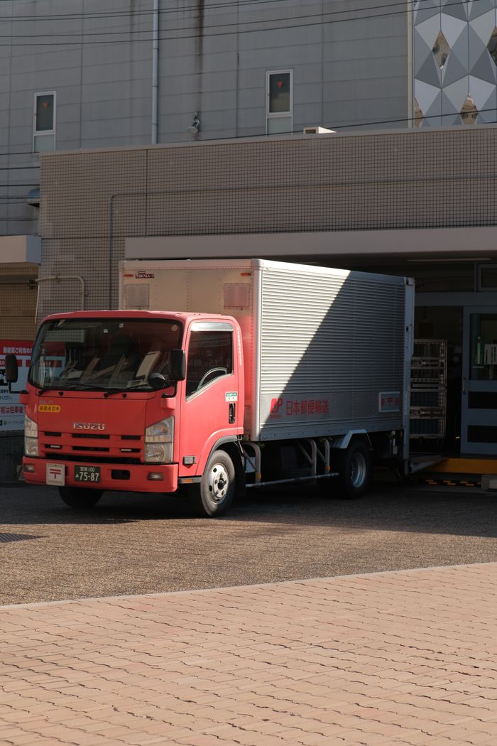 The Art of Drawing Readers In: Your attractive post title goes here A red delivery truck unloading goods at a warehouse on a sunny day in the city.
