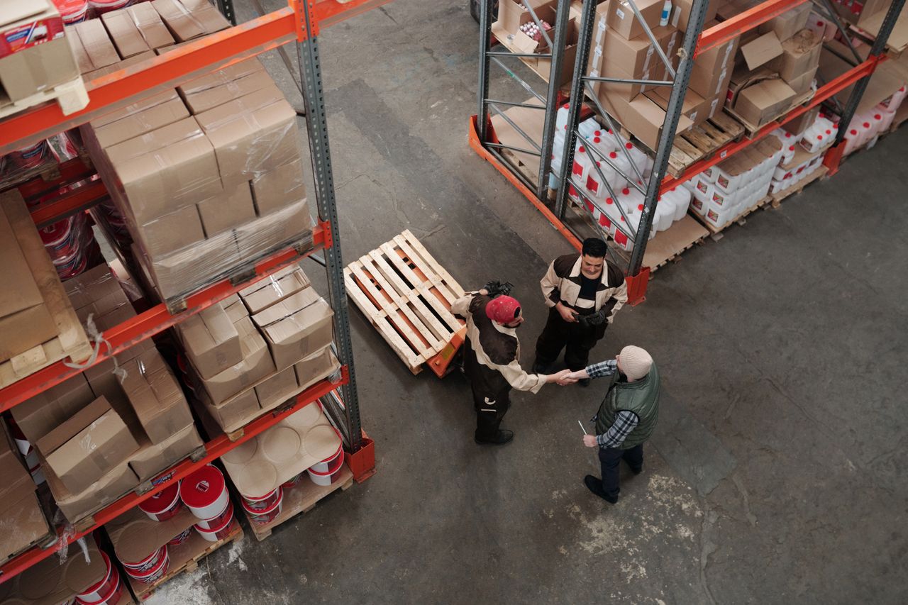 High angle view of workers shaking hands in a warehouse, symbolizing teamwork and logistics.